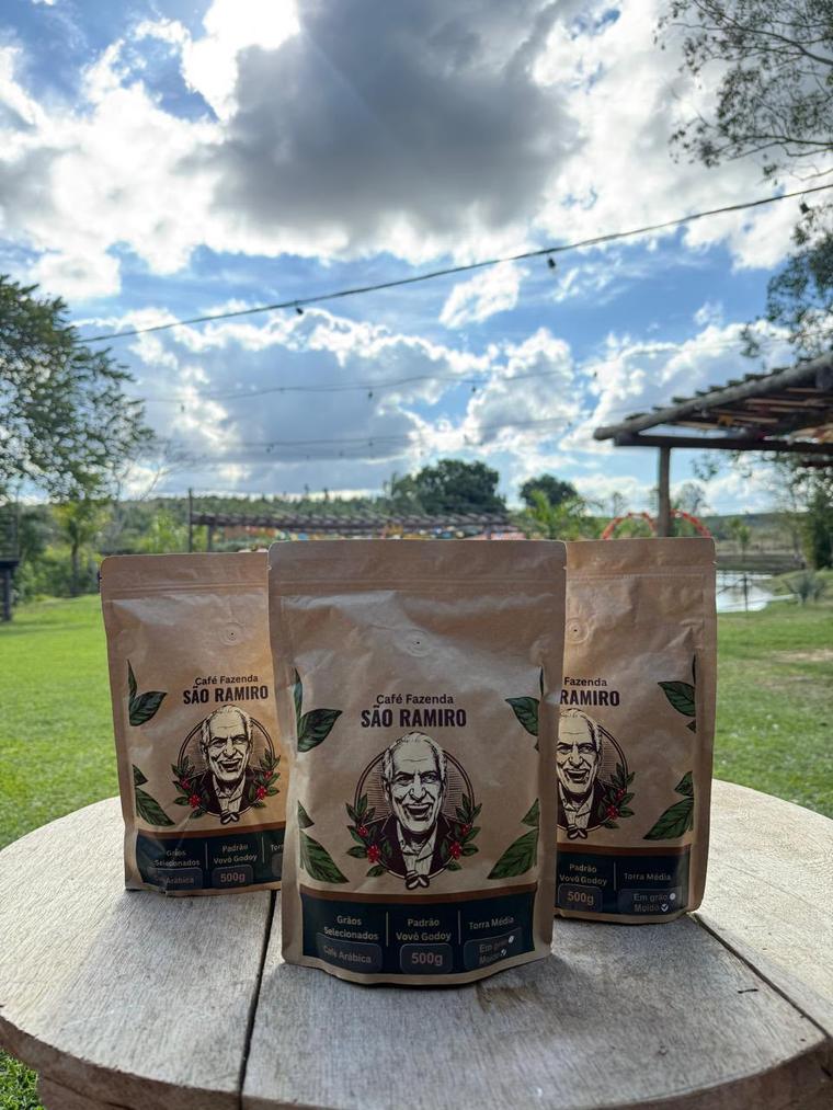 Três pacotes do Café Fazenda São Ramiro sobre uma mesa de madeira na fazenda